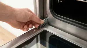 Mano che aziona la leva del cardine dello sportello di un forno aperto