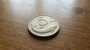 Moneta da 5 lire italiane con delfino del 1956 su superficie in legno